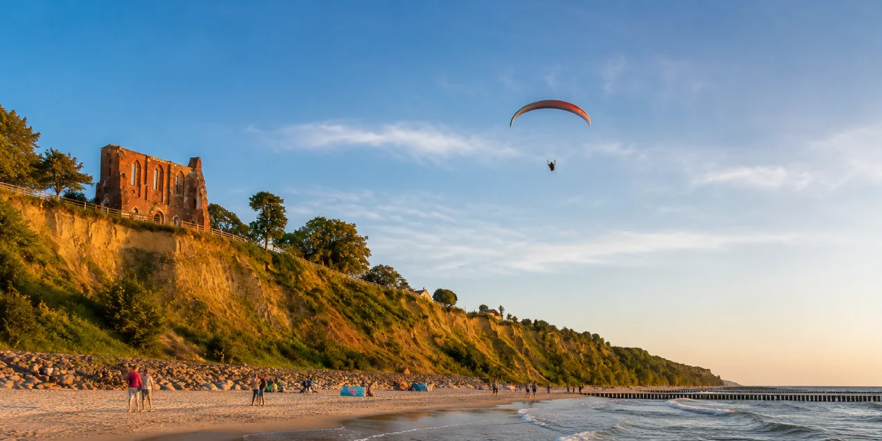 Paralotnia lecąca nad plażą i klifem w Trzęsaczu