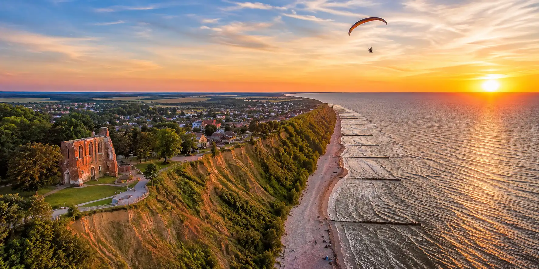 Pilot paralotniowy przygotowujący się do lotu na klifie w Trzęsaczu